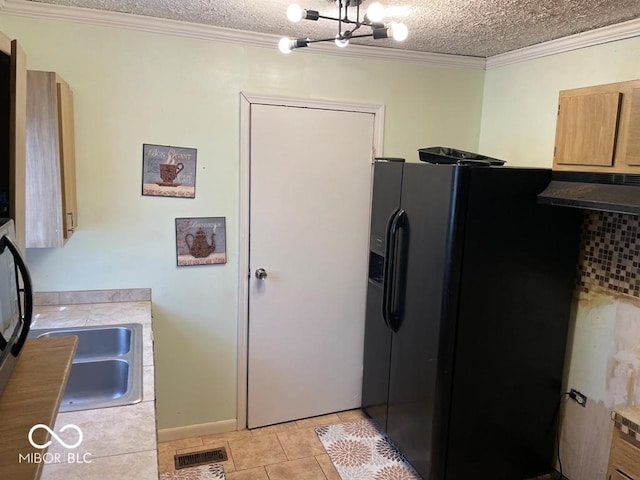 kitchen featuring a textured ceiling, ornamental molding, and black fridge