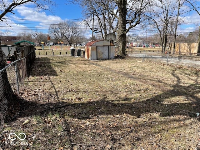 view of yard with a storage shed, fence, and an outbuilding