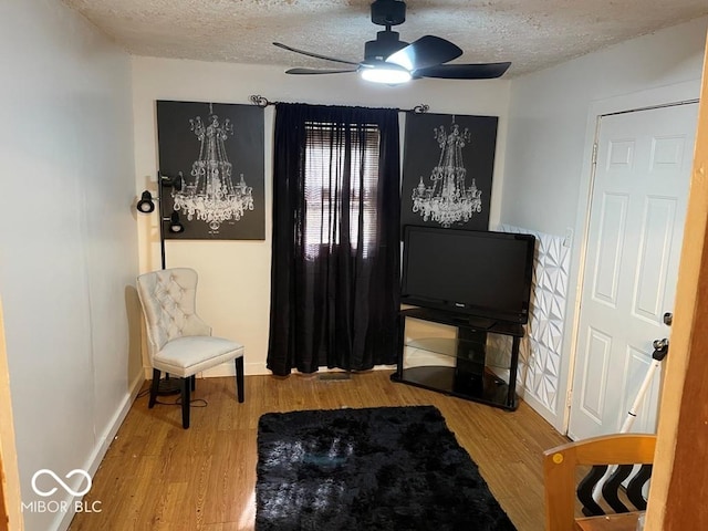 sitting room with a textured ceiling, wood finished floors, and a ceiling fan