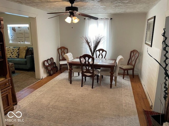 dining room with a textured ceiling, a ceiling fan, light wood-style flooring, and baseboards