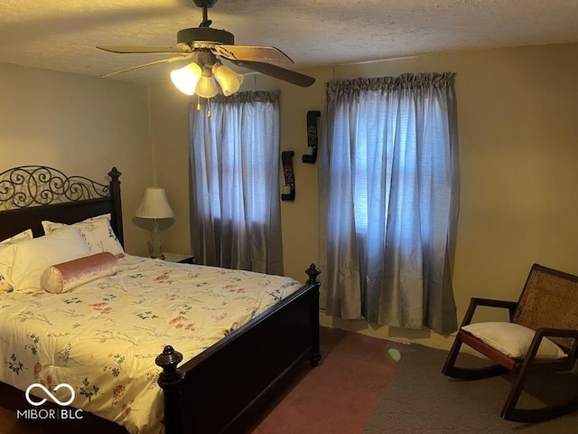 bedroom with a ceiling fan, dark colored carpet, and a textured ceiling