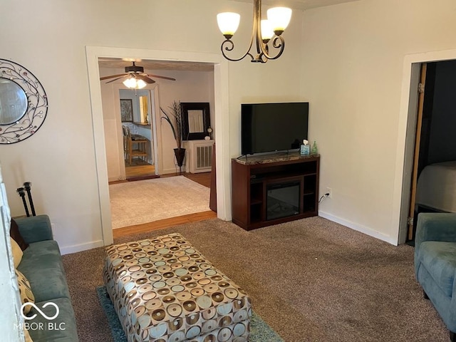 carpeted living area featuring a glass covered fireplace, baseboards, and ceiling fan with notable chandelier