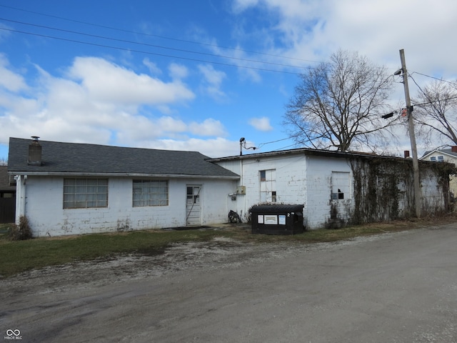 view of front of home featuring concrete block siding and roof with shingles