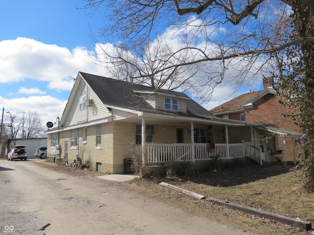 view of front of house featuring driveway, a porch, and an outdoor structure