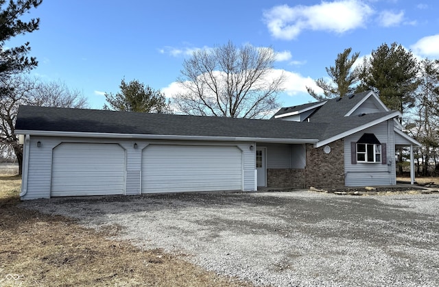 view of front of house with driveway, brick siding, an attached garage, and a shingled roof