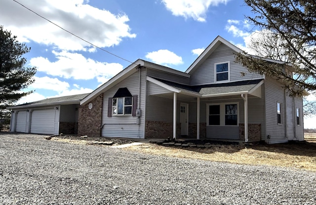 view of front of property with a garage, covered porch, brick siding, and driveway