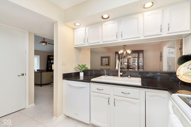 kitchen with white dishwasher, a sink, white cabinets, dark countertops, and range