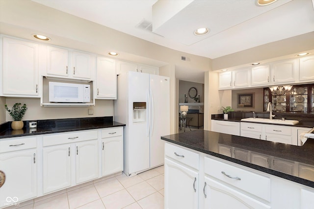 kitchen with white appliances, visible vents, light tile patterned flooring, a sink, and white cabinets