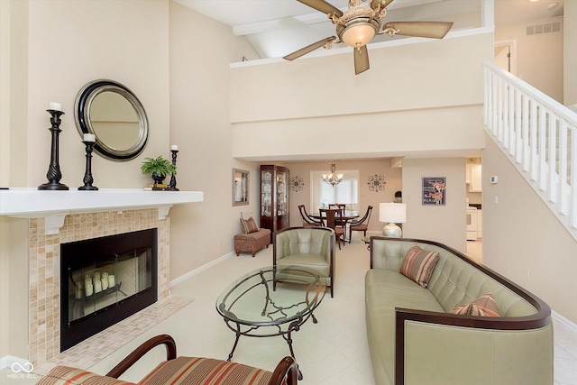 living room featuring stairway, baseboards, visible vents, high vaulted ceiling, and a tile fireplace