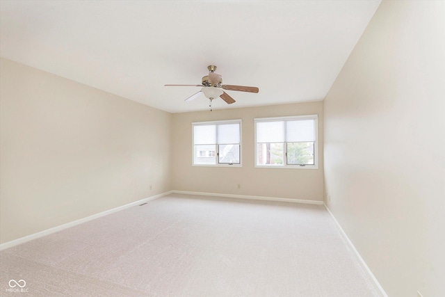 spare room with light colored carpet, baseboards, and ceiling fan