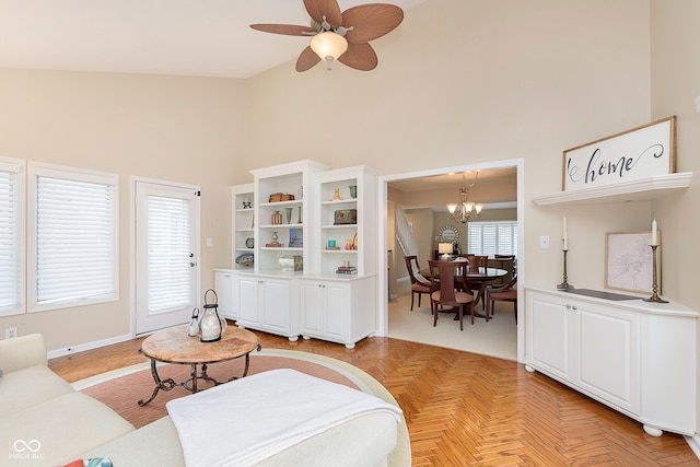 living area featuring ceiling fan with notable chandelier and high vaulted ceiling