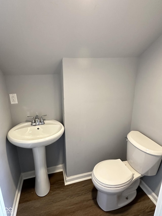 bathroom featuring a sink, wood finished floors, toilet, and baseboards