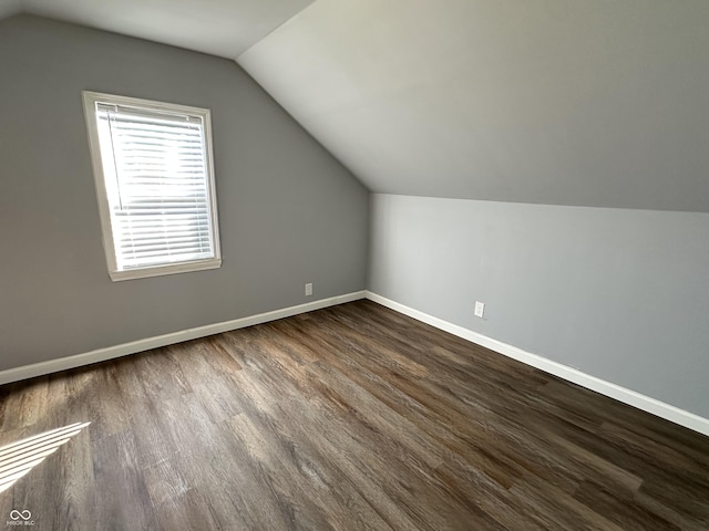 additional living space with baseboards, vaulted ceiling, and dark wood-type flooring