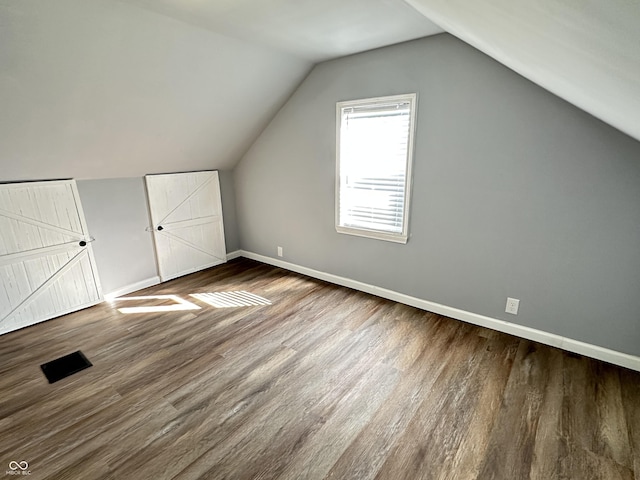 additional living space with lofted ceiling, baseboards, and wood finished floors