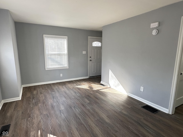 foyer entrance with dark wood-style floors, baseboards, and visible vents