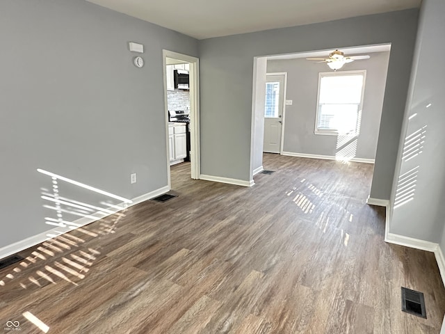 unfurnished living room with baseboards, visible vents, ceiling fan, and wood finished floors