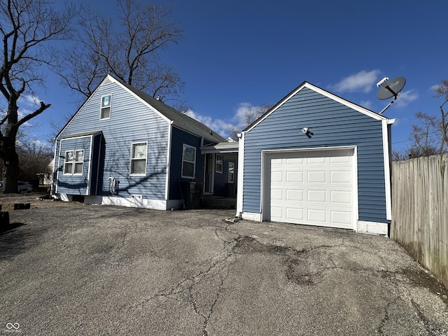 view of front facade featuring aphalt driveway, fence, and a garage