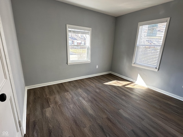 unfurnished room featuring baseboards and dark wood finished floors