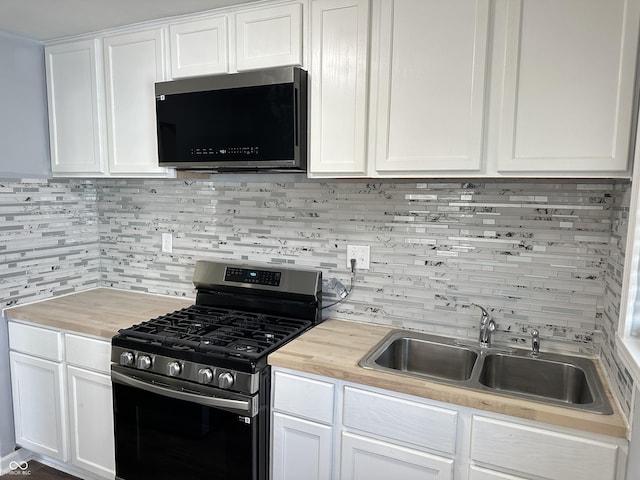 kitchen featuring stainless steel gas range, butcher block counters, white cabinetry, and a sink