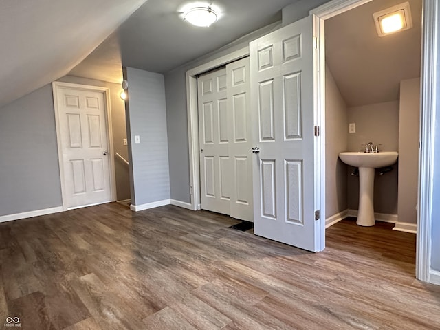 interior space with lofted ceiling, a sink, baseboards, and wood finished floors