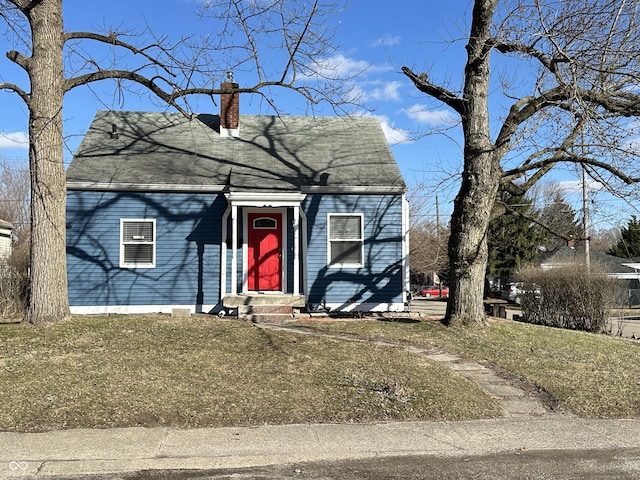 view of front of home with a chimney and a front lawn