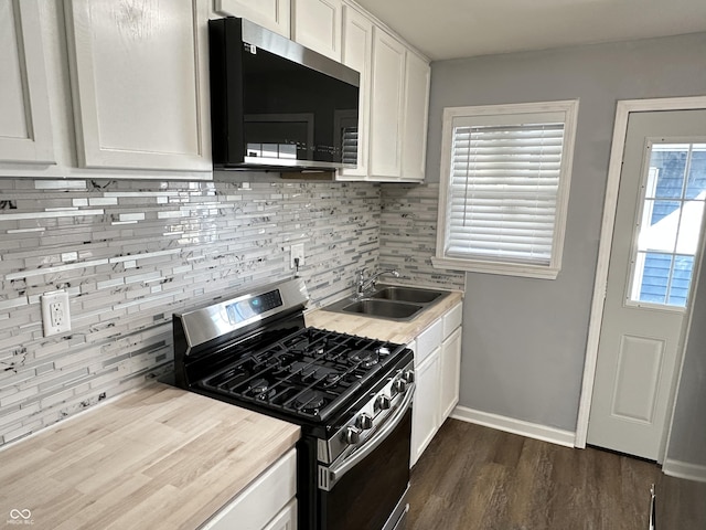 kitchen with light countertops, backsplash, gas stove, white cabinetry, and a sink