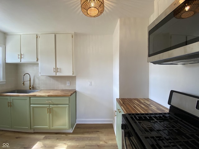 kitchen with a sink, appliances with stainless steel finishes, green cabinets, and wooden counters