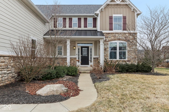 craftsman-style home featuring stone siding, board and batten siding, a front lawn, and a standing seam roof