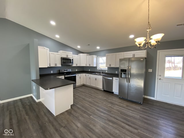 kitchen with stainless steel appliances, dark countertops, vaulted ceiling, a sink, and a peninsula