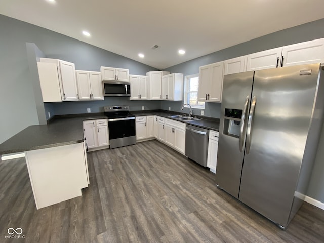 kitchen featuring a peninsula, appliances with stainless steel finishes, dark countertops, and a sink