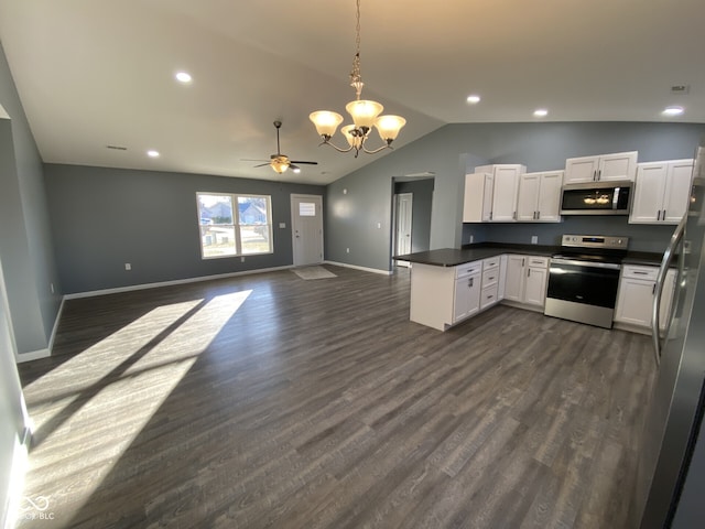 kitchen featuring white cabinets, open floor plan, vaulted ceiling, appliances with stainless steel finishes, and dark countertops