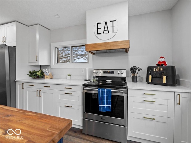 kitchen featuring a textured ceiling, dark wood-style flooring, white cabinetry, freestanding refrigerator, and stainless steel range with electric stovetop