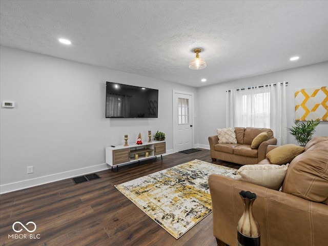 living room featuring a textured ceiling, dark wood-style flooring, visible vents, and baseboards