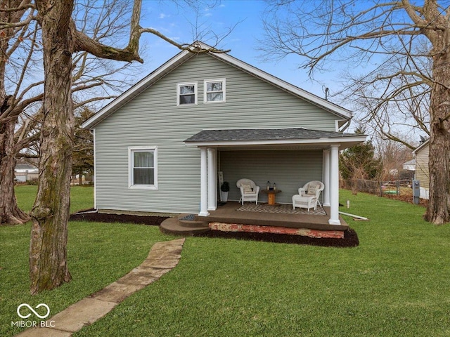 rear view of house with a shingled roof, fence, and a lawn