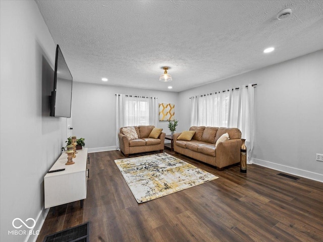 living area featuring baseboards, visible vents, and wood finished floors