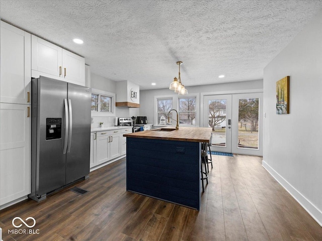 kitchen with french doors, dark wood finished floors, appliances with stainless steel finishes, a sink, and butcher block countertops