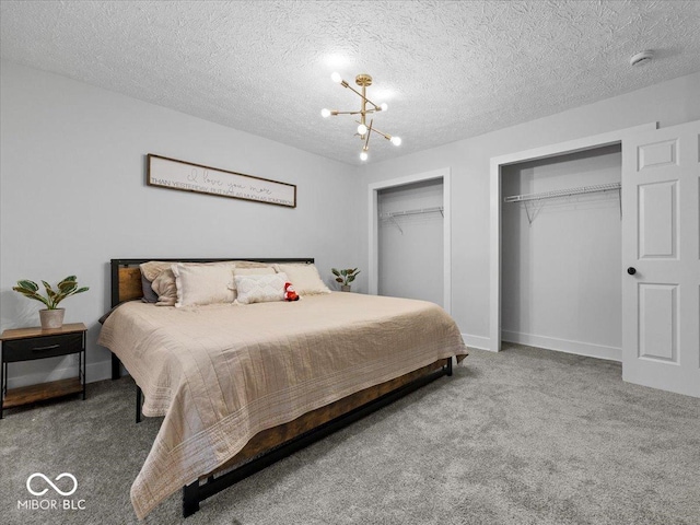 carpeted bedroom featuring an inviting chandelier, a textured ceiling, baseboards, and two closets