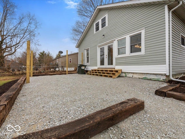 rear view of house with entry steps, fence, and french doors