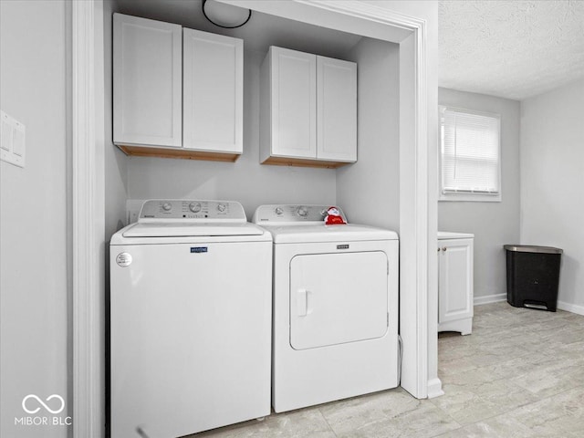 laundry area featuring cabinet space, baseboards, a textured ceiling, and independent washer and dryer