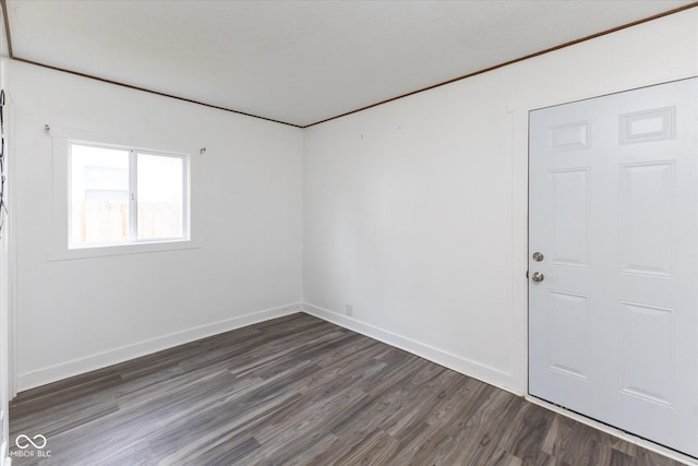 unfurnished room with dark wood-type flooring and baseboards