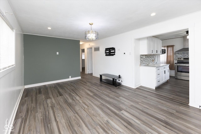 unfurnished living room featuring recessed lighting, a notable chandelier, wood finished floors, visible vents, and baseboards