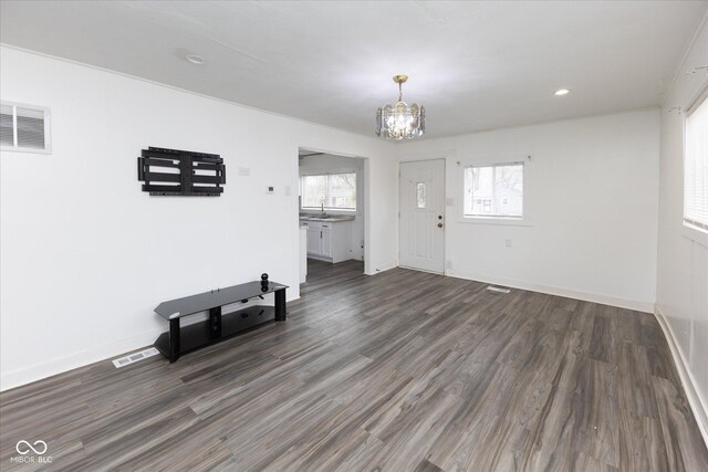 entryway featuring plenty of natural light, dark wood finished floors, visible vents, and an inviting chandelier