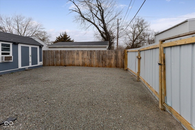 view of yard with a storage shed, a fenced backyard, cooling unit, and an outdoor structure