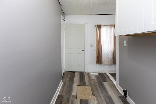 hall with dark wood finished floors, a textured ceiling, and baseboards