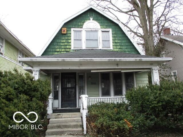 dutch colonial featuring a shingled roof and a porch