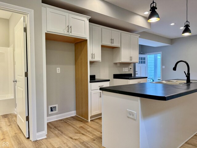 859 N Oakland Ave, Indianapolis, IN 46201 - kitchen with a sink, dark countertops, light wood finished floors, white cabinetry, and pendant lighting