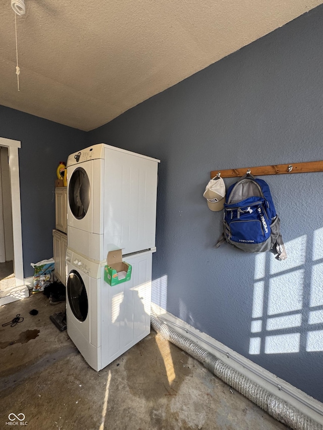 laundry area featuring laundry area, a textured ceiling, and stacked washer / dryer