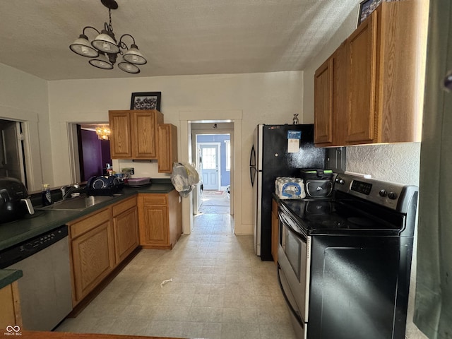 kitchen with a chandelier, stainless steel appliances, a sink, brown cabinetry, and dark countertops