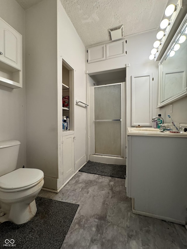 full bathroom featuring a textured ceiling, toilet, visible vents, vanity, and a stall shower