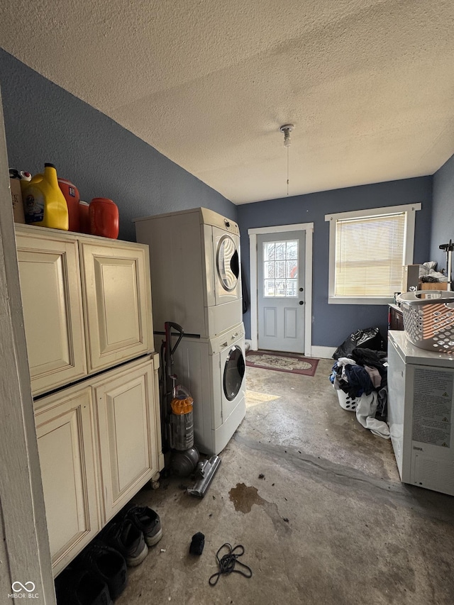 laundry area featuring stacked washer and dryer, a textured ceiling, and cabinet space